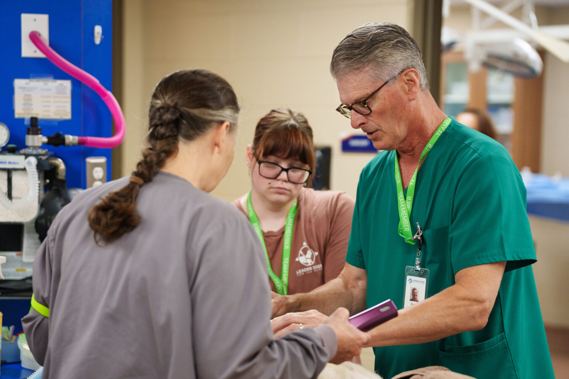 Medical professionals are engaging in a collaborative effort in a clinical setting, focused on a patient care procedure.